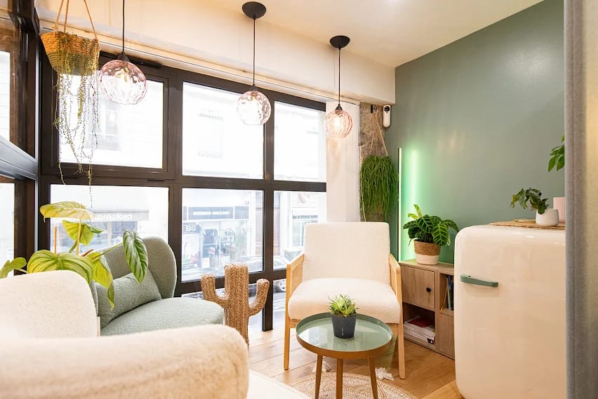 Le coin salon du cabinet, avec fauteuils, plantes vertes et grande baie vitrée sur la rue