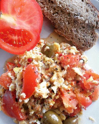 Œufs brouillés, tomates, olives, houmous et chèvre